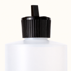 Close-up of the Care Oil bottle’s black dispensing cap, narrow spout and white neck