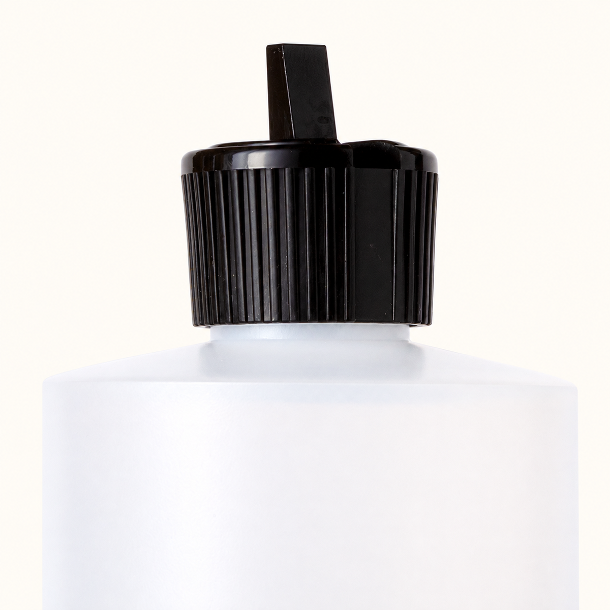 Close-up of the Care Oil bottle’s black dispensing cap, narrow spout and white neck