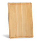 Maple cutting board with a juice groove standing on its short edge, viewed at an angle