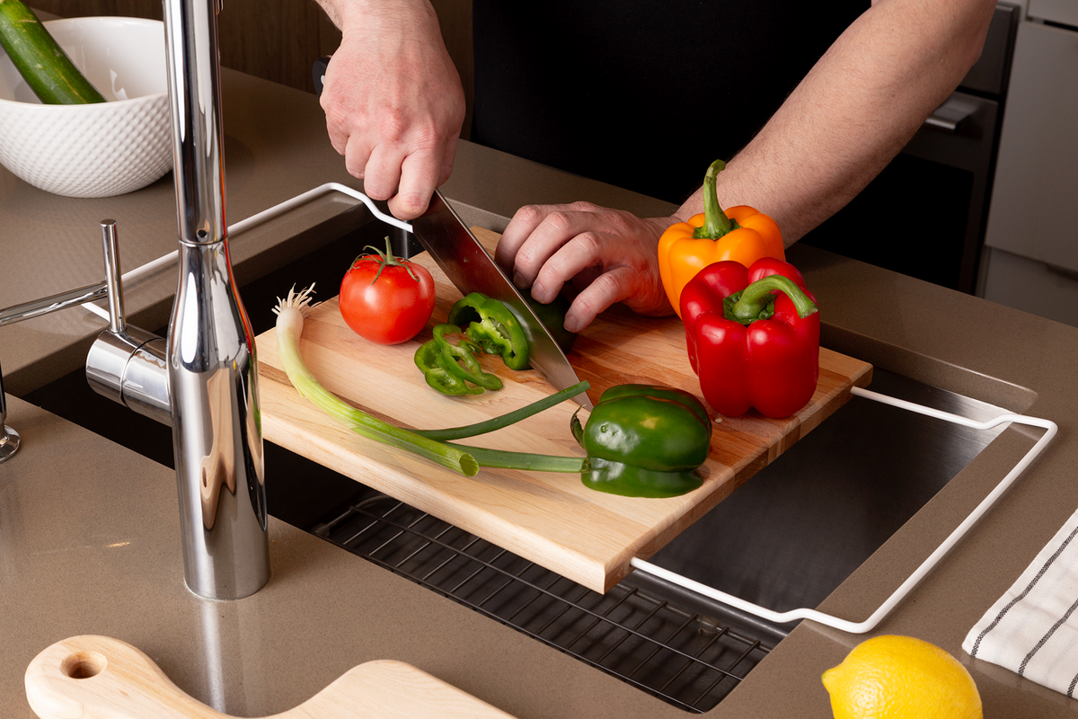 Over-the-sink wooden cutting board used to prepare vegetables