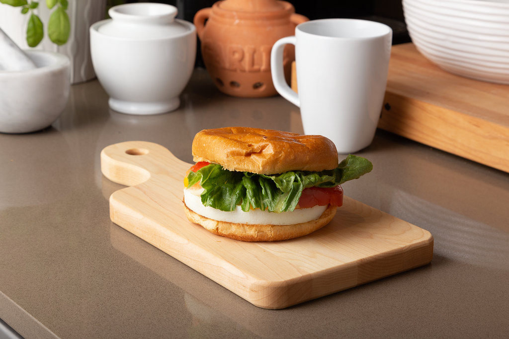 Small maple serving board with handle, 12 × 6 in with an egg breakfast sandwich