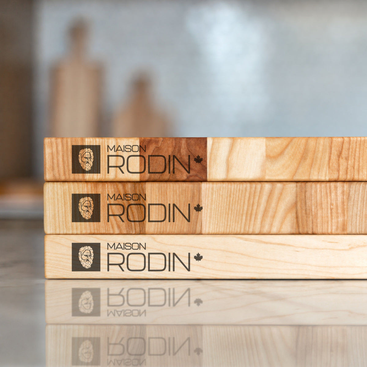 Stacked Maison Rodin wooden boards showing their grain and branded edges